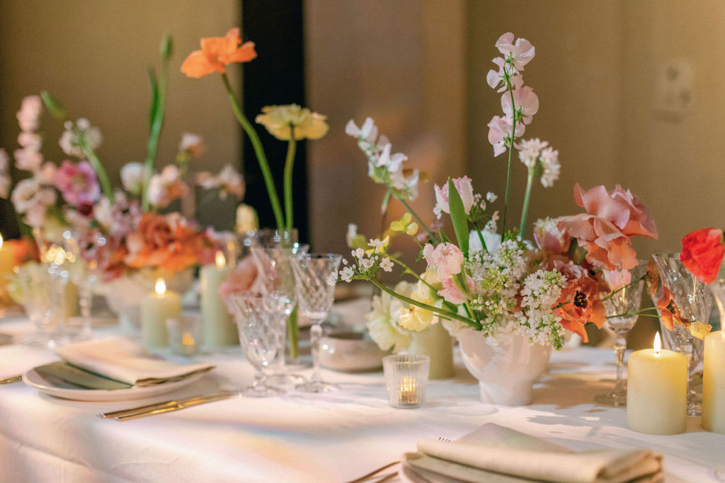 A table set for a formal dinner dressed in a damask table cloth beautifully decorated with natural-looking flowers