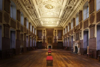 Interior of room with decorative ceiling, wooden floor and decorative features on the walls.