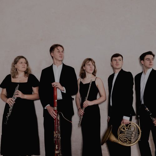 Standing group of three men and two women holding instruments.
