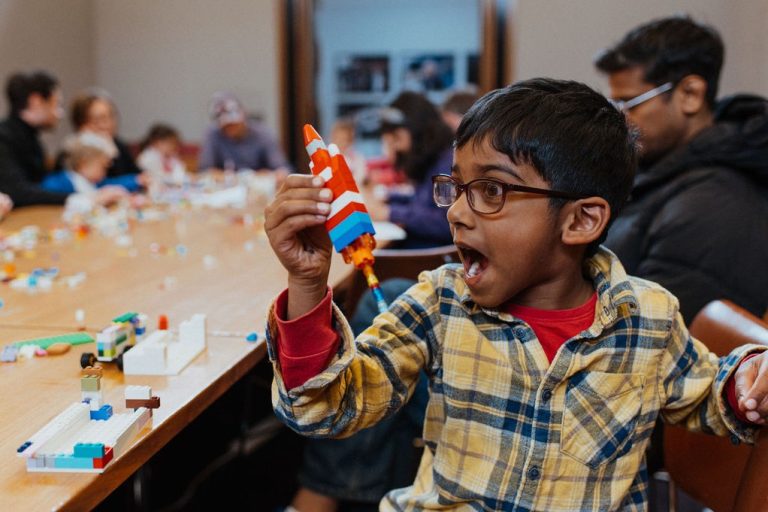 Boy holding a rocket made from LEGO in his right hand.