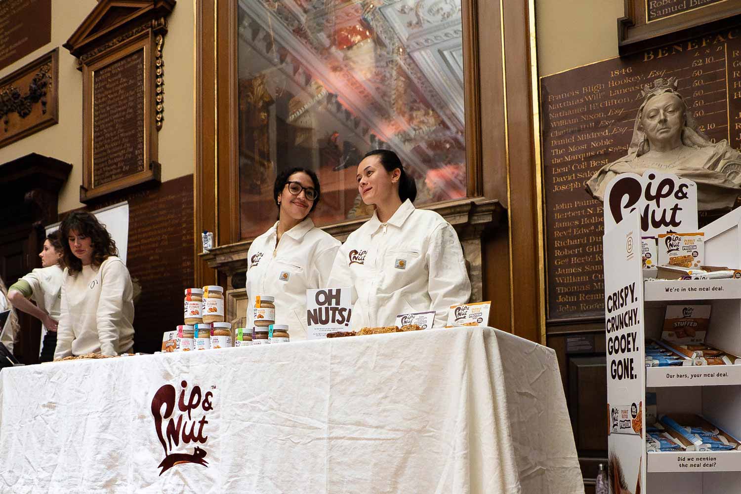 Two women stand behind their stall presenting their products at the Great Hall