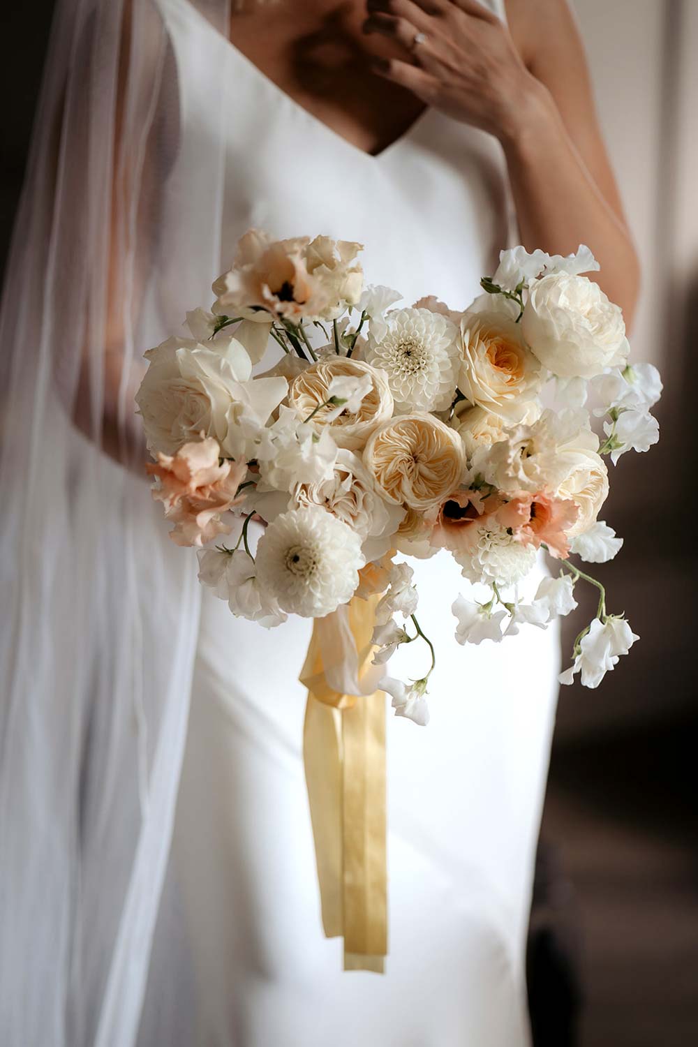A bride holds a bouquet of white and pink flowers