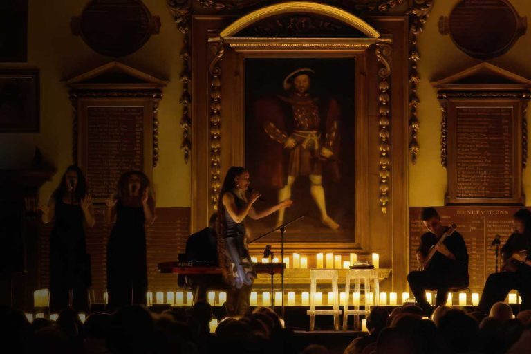 A singer on stage in the Great Hall performing at a candlelit concert