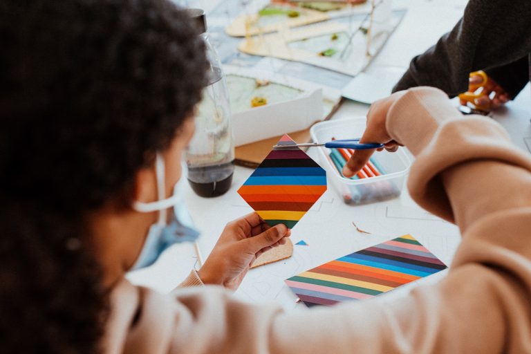 Person cutting a multi-coloured square.